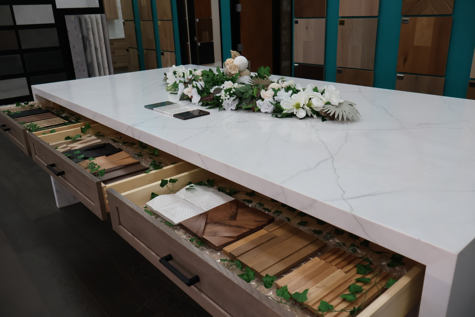 Elegant Surface Pros showroom selection table with polished white quartz countertop and open drawers showcasing wood and tile samples